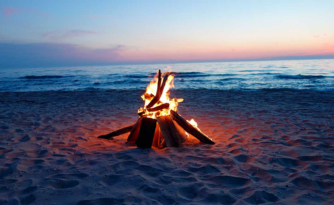 A vibrant sunset over South Padre Island, featuring a bonfire on the beach, creating a relaxing atmosphere.