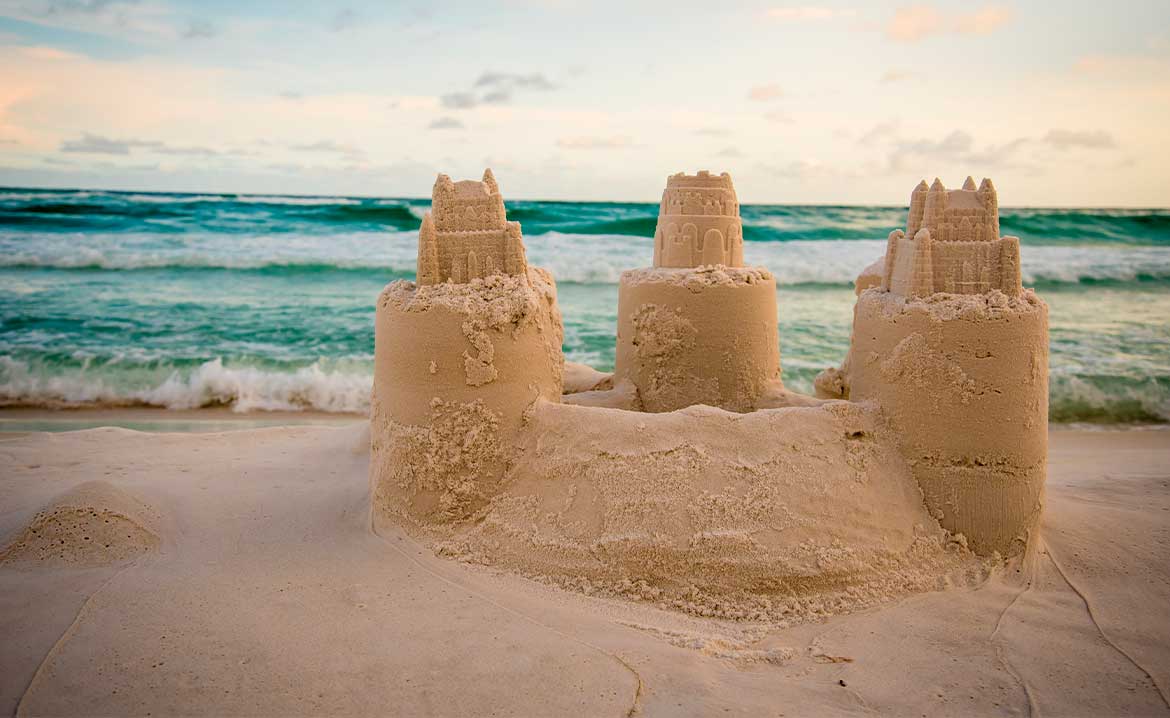 Sunset casts a golden glow on a sand castle at the beach, capturing the serene vibe of South Padre Island.