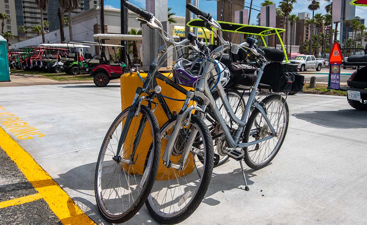 Two bicycles are parked in a parking lot, showcasing transportation tips for larger groups at South Padre Island.
