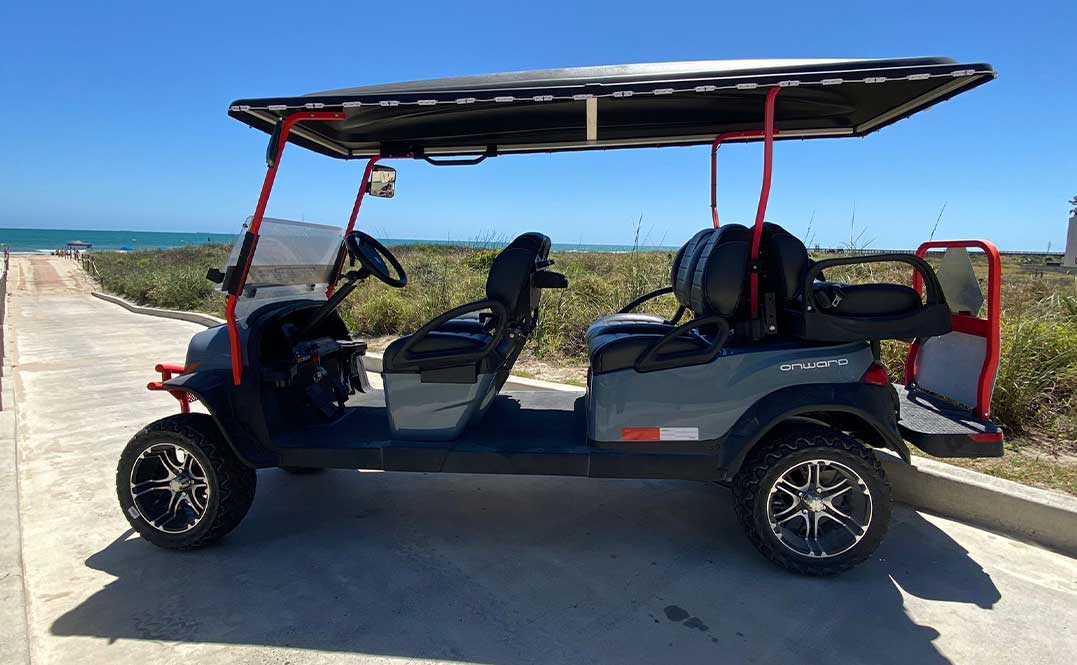A beach scene featuring a 6 seater golf cart with a canopy, emphasizing the traffic laws for golf carts on South Padre Island.