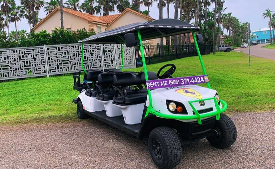 A golf cart with a "lawn service" sign, adhering to South Padre Island's golf cart traffic laws.