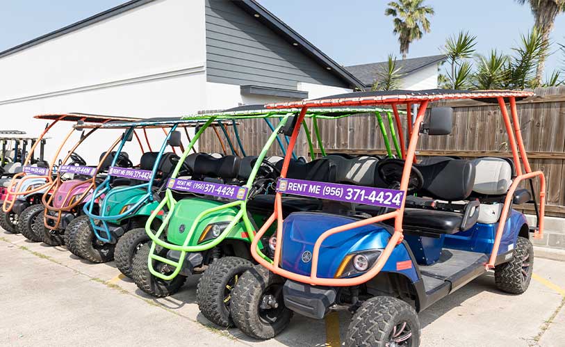 Vibrant golf carts, including 4-seater and 8-seater options, lined up in front of a building, ideal for your SPI adventure.