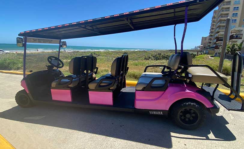 A pink and black golf cart featuring side seating, suitable for discussing 4-seater vs 8-seater choices for SPI trips.