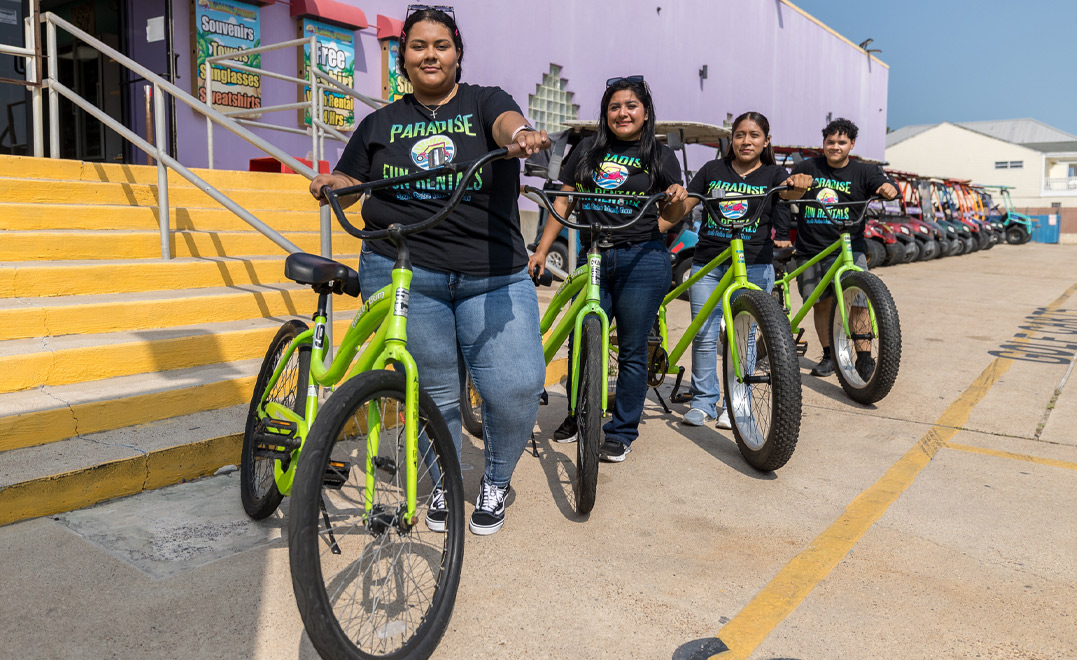 Four Paradise Fun Rentals team members smile while posing with their bikes.