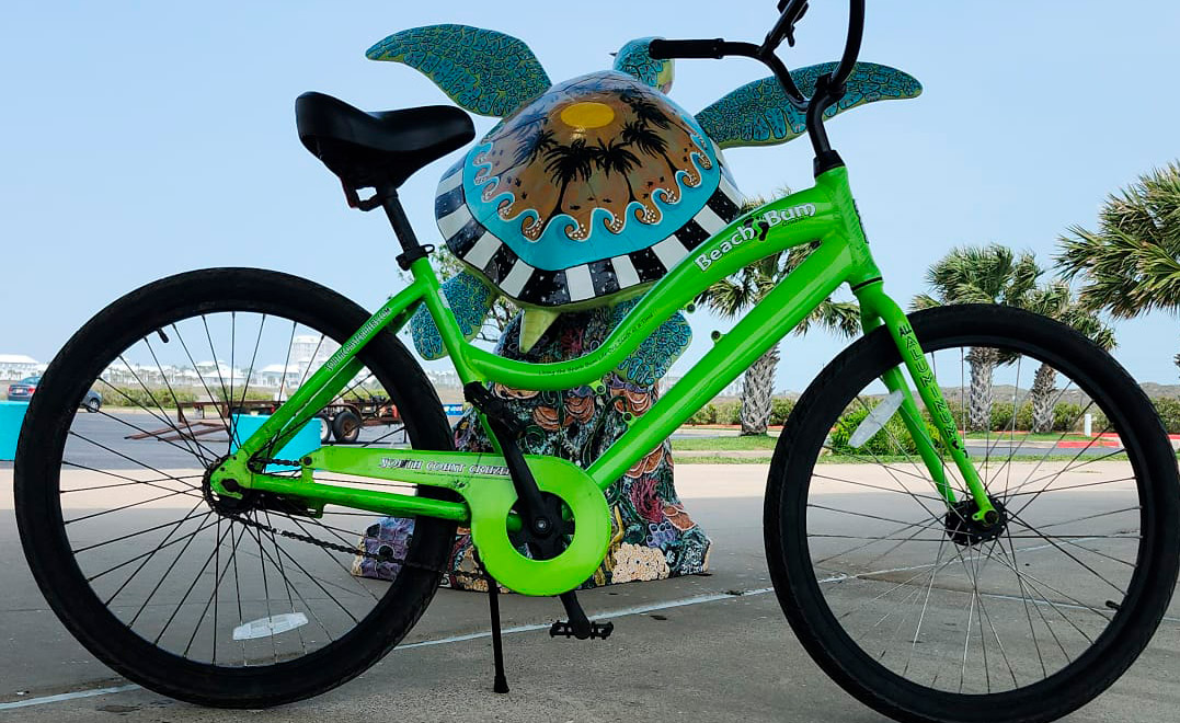 A green regular bike stands next to a turtle statue, representing bike rental options in South Padre.