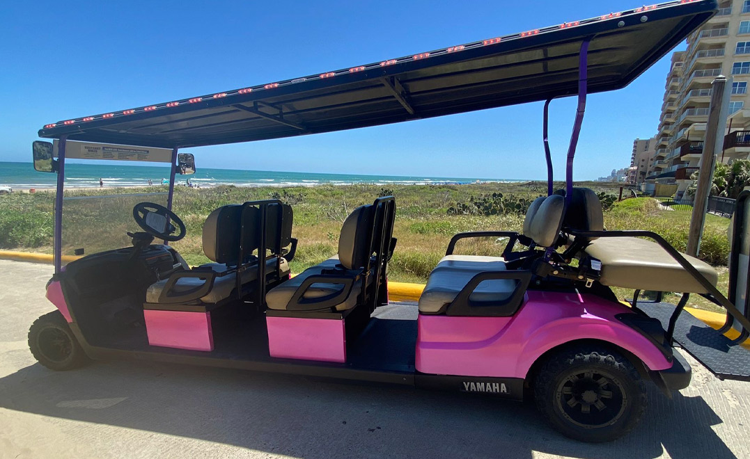 A pink and black golf cart with seats, ideal for exploring South Padre Island with your group.