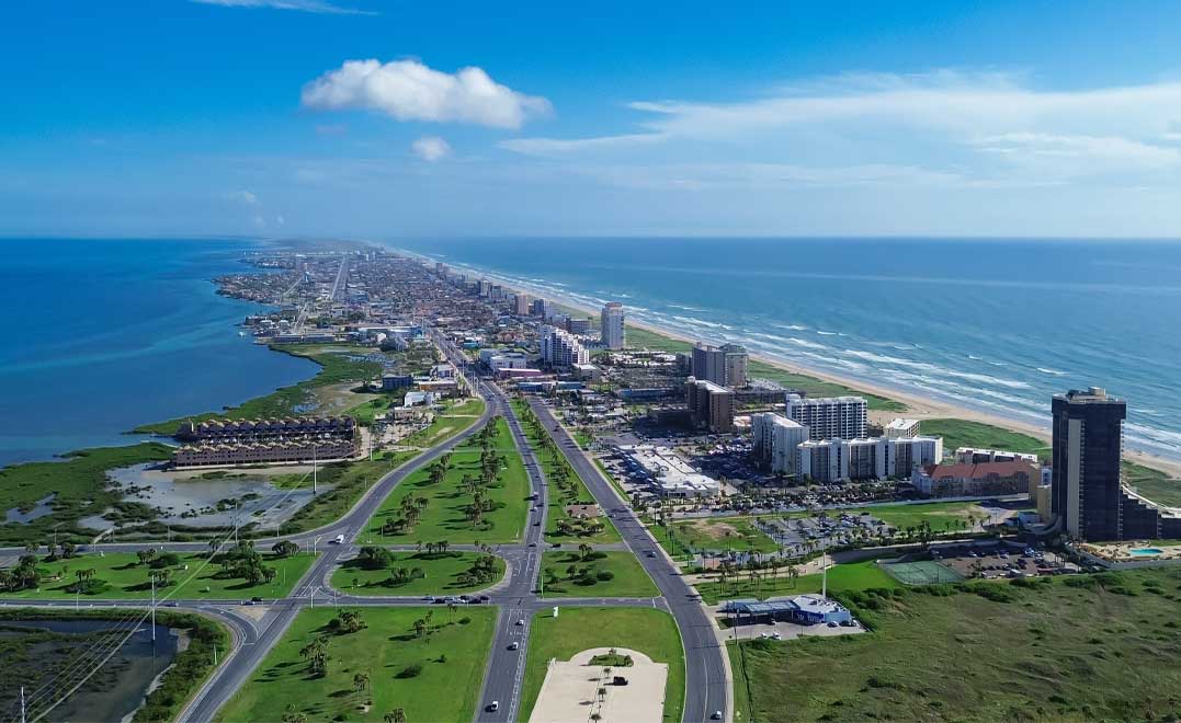Downtown South Padre Island along Padre Boulevard, State Park Road 100 from Isla Blanca Beach, high-rise condos, beach-front hotels, white sandy beaches turquoise water, calm waves, aerial view. USA